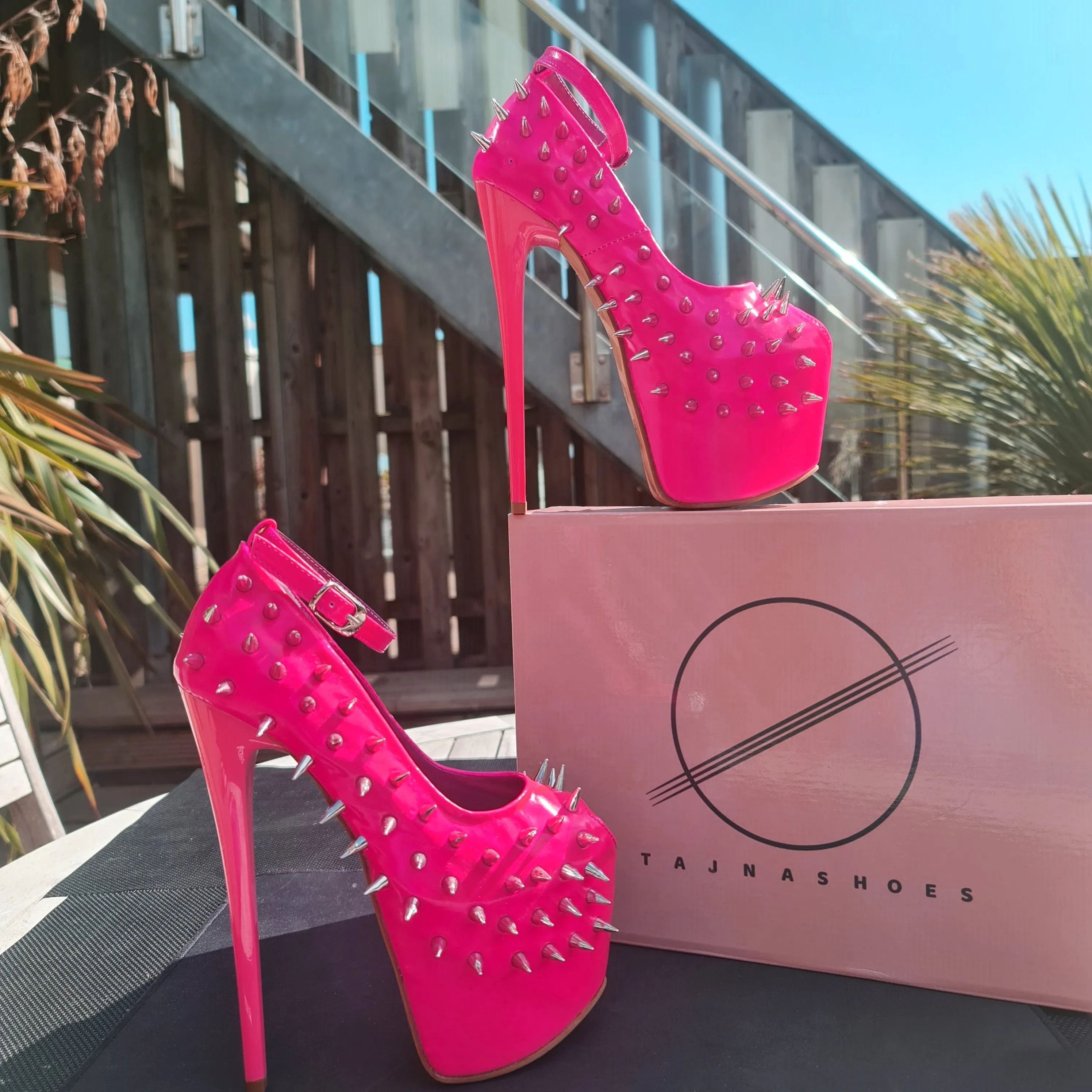 Glossy hot neon pink ankle strap heels with spike studs.